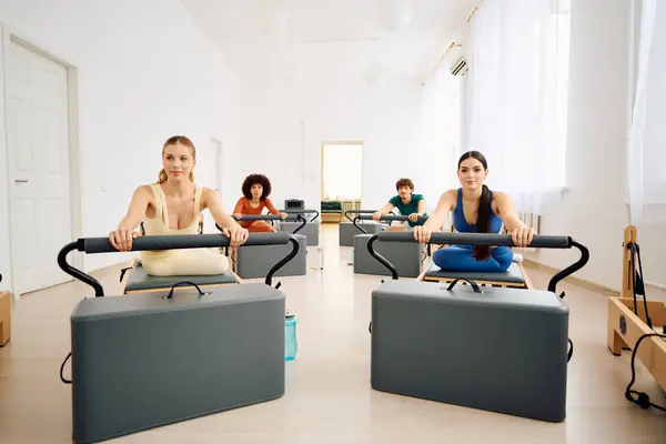 Quattro individui in uno studio sereno mostrano forza e concentrazione durante una lezione di pilates. — Foto stock
