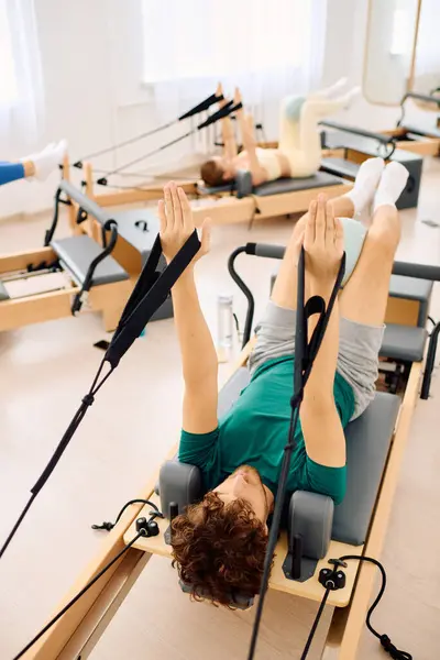 Los participantes toman una clase de pilates enfocada usando equipo especializado para fuerza y flexibilidad. - foto de stock