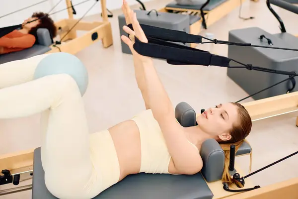 Individui concentrati praticano tecniche di pilates in uno studio elegante pieno di attrezzature. — Foto stock