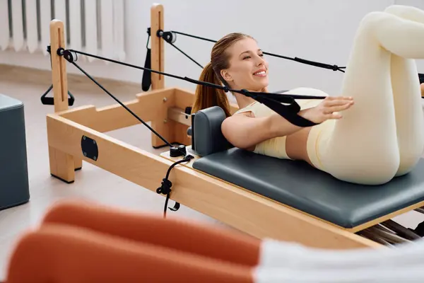 A woman performs a dynamic Pilates workout with equipment for core strength and flexibility. — Stock Photo