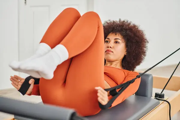 A dedicated athlete engages in a pilates workout using reformer equipment in a serene studio. — Stock Photo