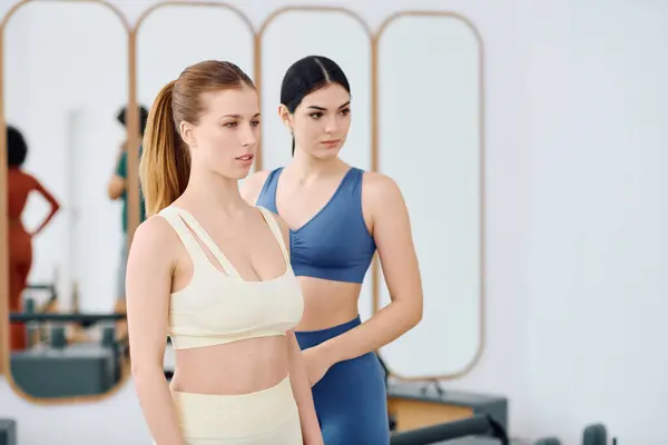Two women practice pilates with concentration in a spacious, sunlit studio setting. — Stock Photo