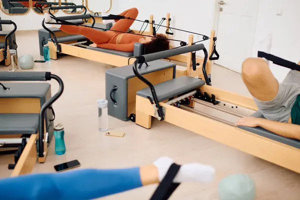 A group takes a tough pilates class with reformer machines for strength training. — Stock Photo