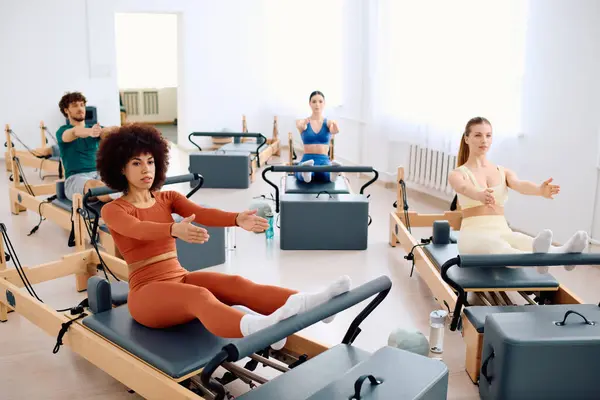Os participantes se envolvem em exercícios de pilates em reformadores, aumentando a força e flexibilidade. — Fotografia de Stock