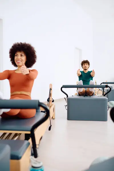 Duas pessoas fazem um treino de pilates focado para aumentar a força e flexibilidade em um estúdio brilhante. — Fotografia de Stock