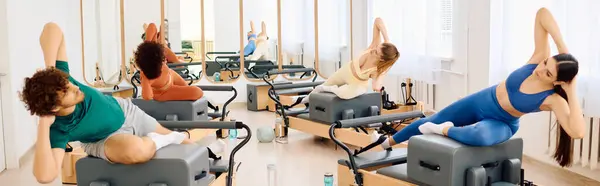 Group of individuals engaged in dynamic pilates exercises in a bright and spacious studio. — Stock Photo