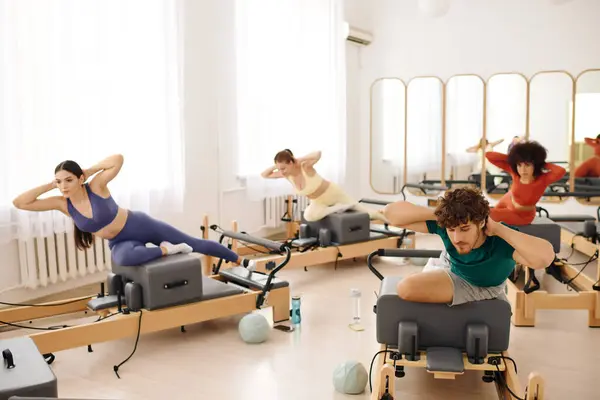 Os participantes se envolvem em exercícios intensos de pilates usando equipamentos especializados durante uma aula animada — Fotografia de Stock