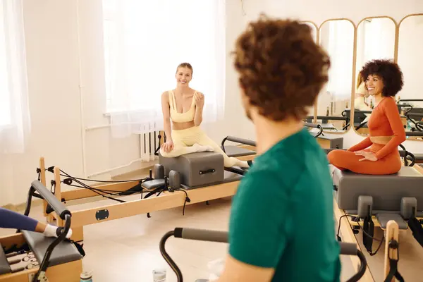 Participants enjoy a dynamic pilates session while sharing smiles and motivation in a lively studio — Stock Photo