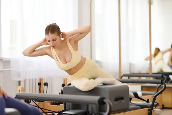 A woman practices advanced pilates in a serene studio filled with natural light. — Stock Photo