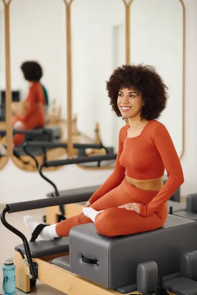 A woman in bright athletic wear reflects while doing pilates in a sunny studio. — Stock Photo
