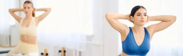 Duas pessoas fazem pilates, com foco na postura e na força do núcleo em um estúdio iluminado pelo sol. — Fotografia de Stock