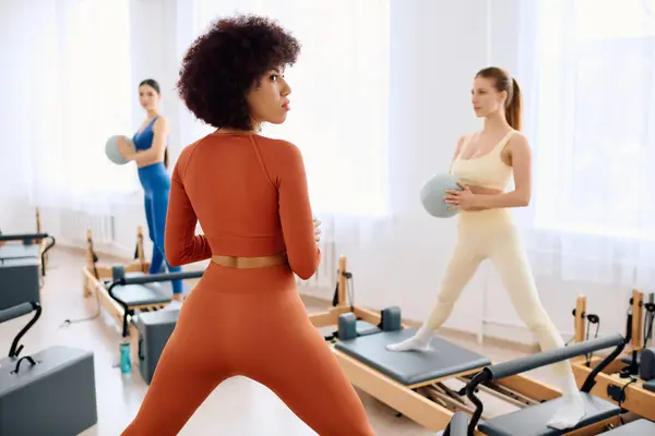 Tre persone si impegnano in un allenamento dinamico pilates in un ambiente spazioso monolocale. — Foto stock