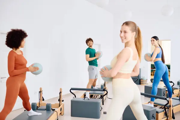 Vier Personen genießen einen lebhaften Pilates-Kurs und zeigen in einem hellen Studio Athletik und Kameradschaft. — Stockfoto