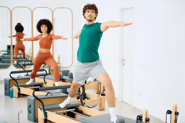 Dois indivíduos realizam Pilates dinâmicos em um estúdio iluminado pelo sol, exibindo foco e determinação. — Fotografia de Stock