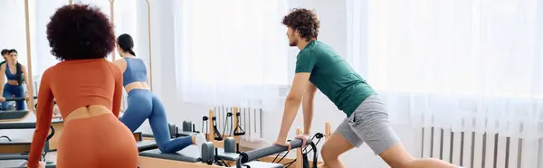 A dedicated group practices stretching and strengthening on reformer machines in natural light. — Stock Photo