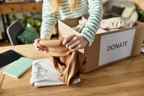 Young woman carefully organizes her clothes for donation, promoting a sustainable lifestyle. — Stock Photo