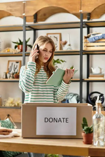 A young woman sorts clothes for donation during a phone call in a cozy setting. — Stock Photo