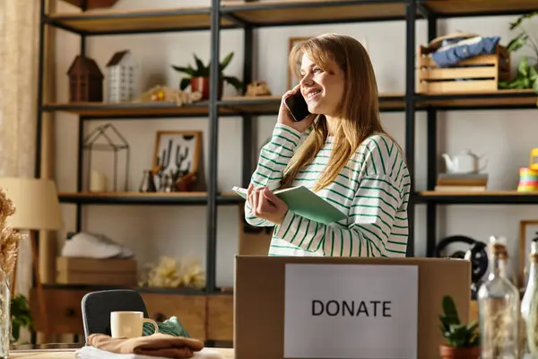 A young woman smiles as she organizes clothes for donation, embracing sustainability. — Stock Photo