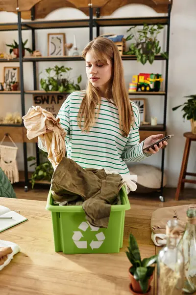 Uma jovem classifica suas roupas para reciclagem enquanto promove um estilo de vida sustentável dentro de casa. — Fotografia de Stock