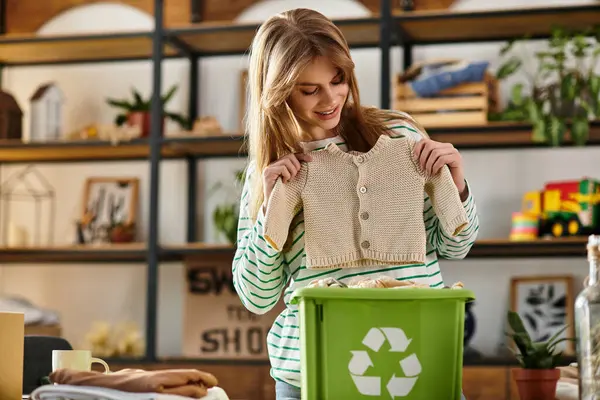 Young woman joyfully sorts and recycles her clothing in a cozy, eco-friendly space. — Stock Photo