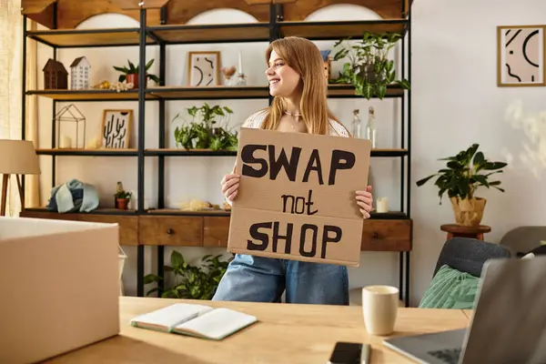 Pretty young woman holds a sign promoting sustainability while sorting her clothes for donation. — Stock Photo