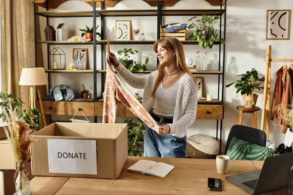 A woman happily organizes her clothing donations, embracing a sustainable lifestyle at home. — Stock Photo