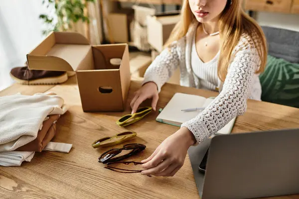 Young woman organizes clothes and sunglasses for recycling in her home office. — Stock Photo
