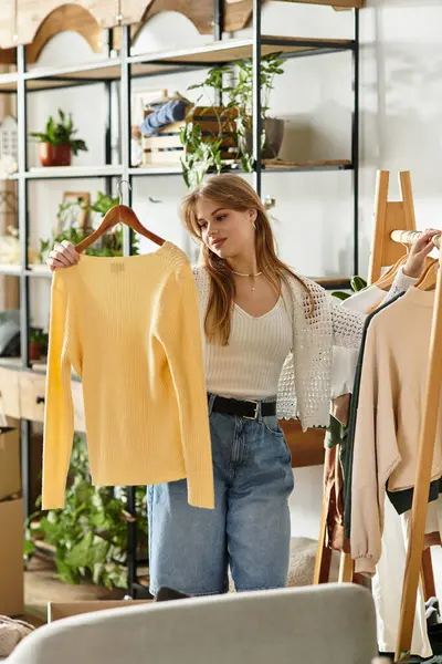 Pretty young woman sorts her clothes in a cozy, plant-filled space for donation. — Stock Photo