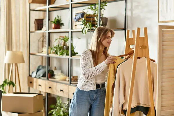 In a cozy living space, a young woman organizes her clothes to donate, embracing sustainability. — Stock Photo