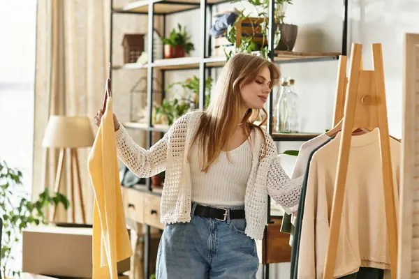 A young woman sorts her clothes for donation, promoting sustainability. — Stock Photo