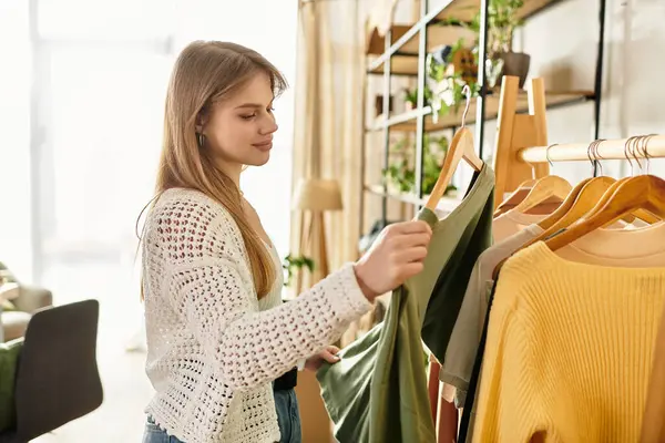 A young woman organizes her clothes, preparing them for donation in a bright room. — Stock Photo