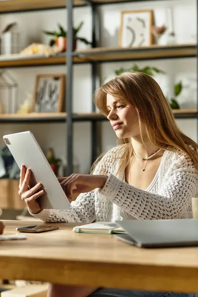 Young woman actively donating clothes, using tablet and embracing a sustainable lifestyle at home. — Stock Photo