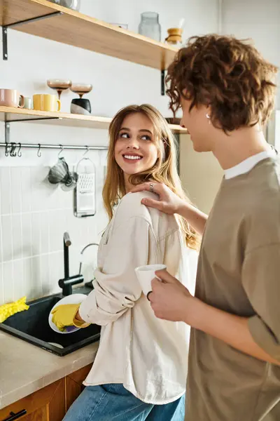 A joyful couple enjoys a loving interaction while washing dishes, creating a warm home atmosphere. — Stock Photo