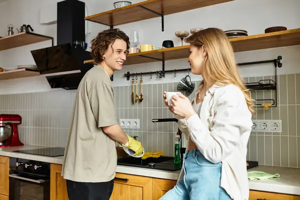 Couple enjoys each others company as they clean and discuss over coffee in a cozy kitchen — Stock Photo