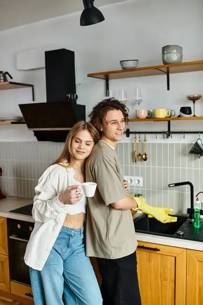 Una coppia amorevole condivide un momento nella loro cucina, una pulisce mentre l'altra si rilassa. — Foto stock