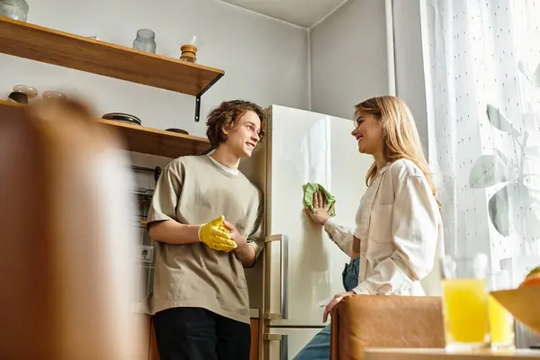 Young couple happily interacts while tidying up their modern kitchen in a comfortable home setting. — Stock Photo