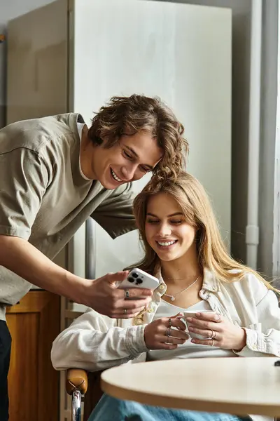 Sweet couple enjoys each others company while engaging with a mobile device in their home. — Stock Photo