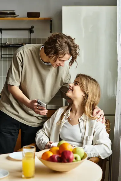 A young couple shares a sweet moment at home, smiling together amidst fresh fruits. — Stock Photo