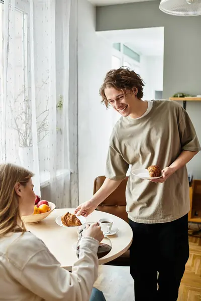 A loving young couple shares a warm breakfast, filled with laughter in their cozy space. — Stock Photo