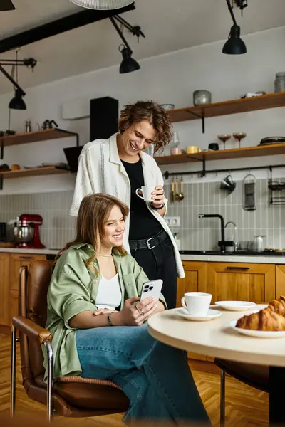 Due partner condividono un momento di gioia a casa, gustando caffè e dolci mentre si connettono. — Foto stock