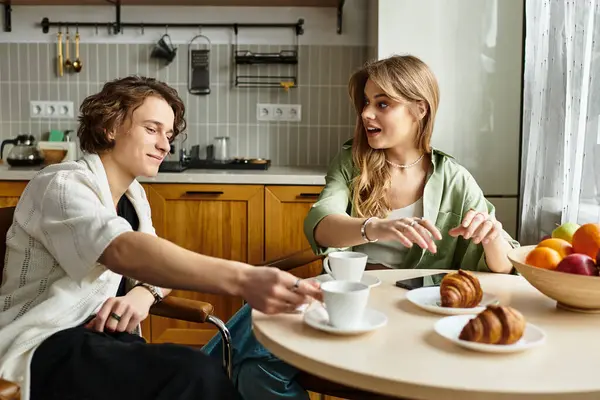 Pareja cariñosa comparte una mañana encantadora juntos sobre café y pasteles en una acogedora cocina. - foto de stock