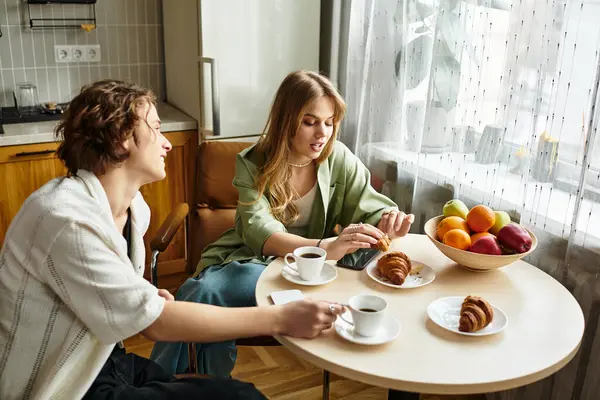 Young couple enjoys a cozy breakfast at home with pastries and coffee. — Stock Photo