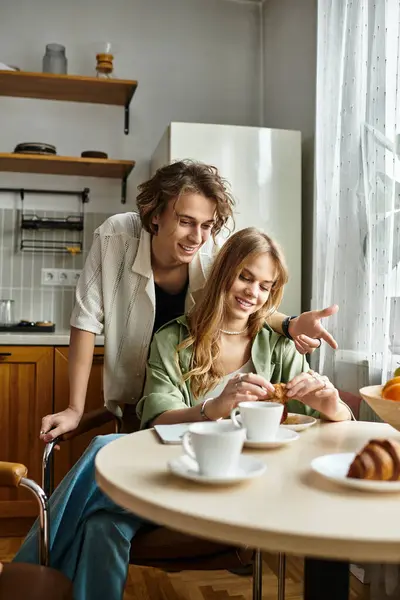A loving couple enjoys breakfast together, sharing smiles and pastries in their inviting kitchen. — Stock Photo