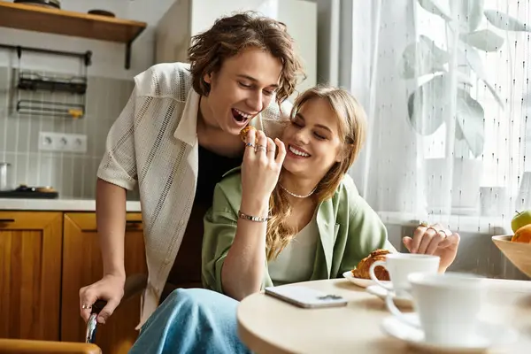 A loving couple smiles and playfully shares food in a modern, comfy kitchen filled with warmth. — Stock Photo