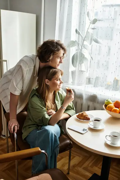 A young couple shares smiles over breakfast in their cozy kitchen, savoring pastries. — Stock Photo