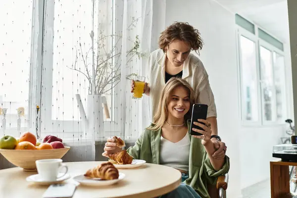 A young couple shares a joyful morning together, enjoying pastries and fruit while smiling. — Stock Photo