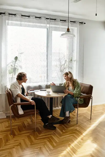 Young couple enjoys each others company at home while working on a laptop and sipping drinks. — Stock Photo
