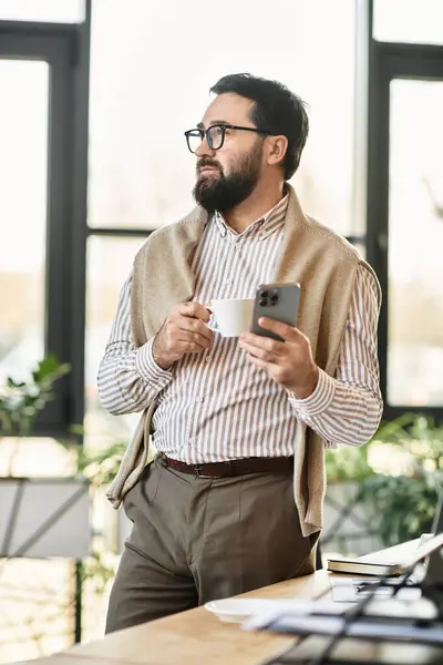 Senior man in casual attire stands confidently, sipping coffee and engaging with technology. — Stock Photo