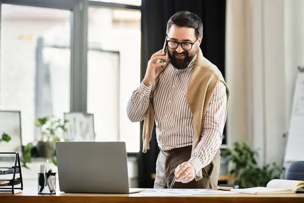 An elderly man smiles while on a phone call, dressed casually and enjoying his office environment. — Stock Photo