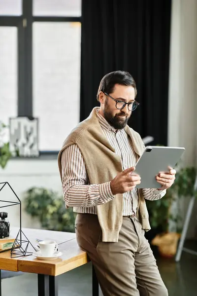 Handsome elderly man dressed casually examines his tablet with interest in a cozy indoor setting. — Stock Photo
